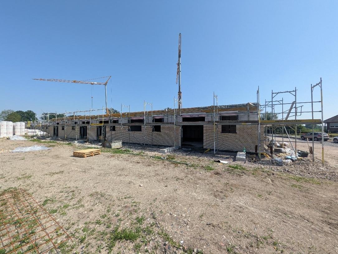 Gesamtansicht der Baustelle mit Klinkerfassade und Gerüst