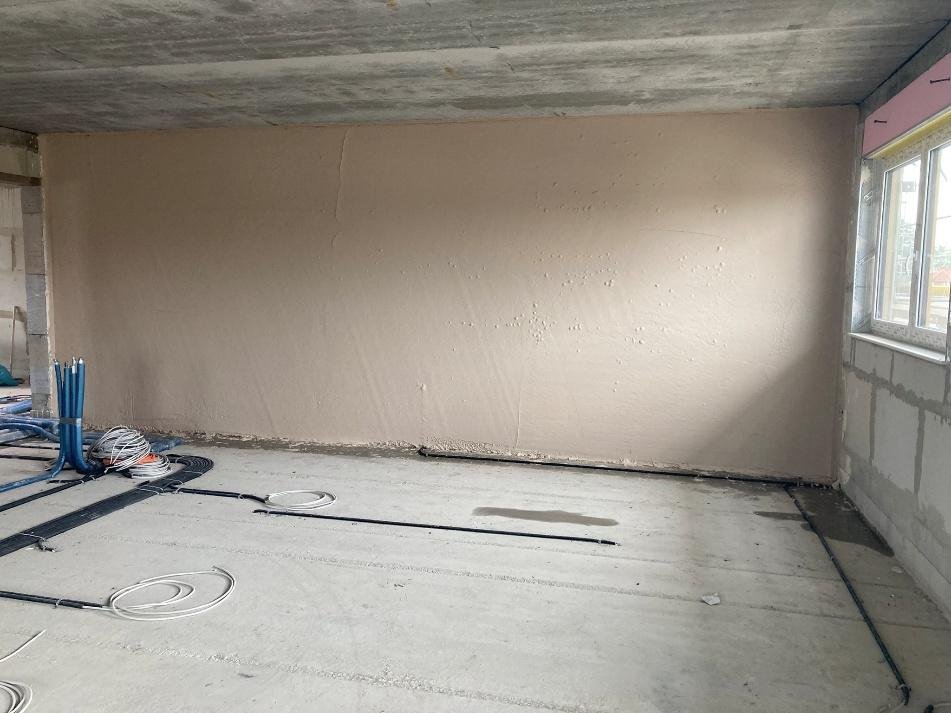 Frisch verputzte Innenwand in Haus 2, auf dem Boden verlegte Leerrohre für die Haustechnik