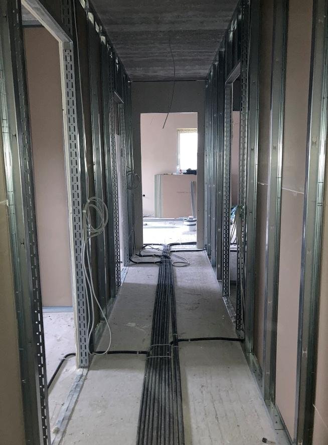 Flur im Innenausbau mit Metallständerwänden, auf dem Boden gebündelte Kabelstränge